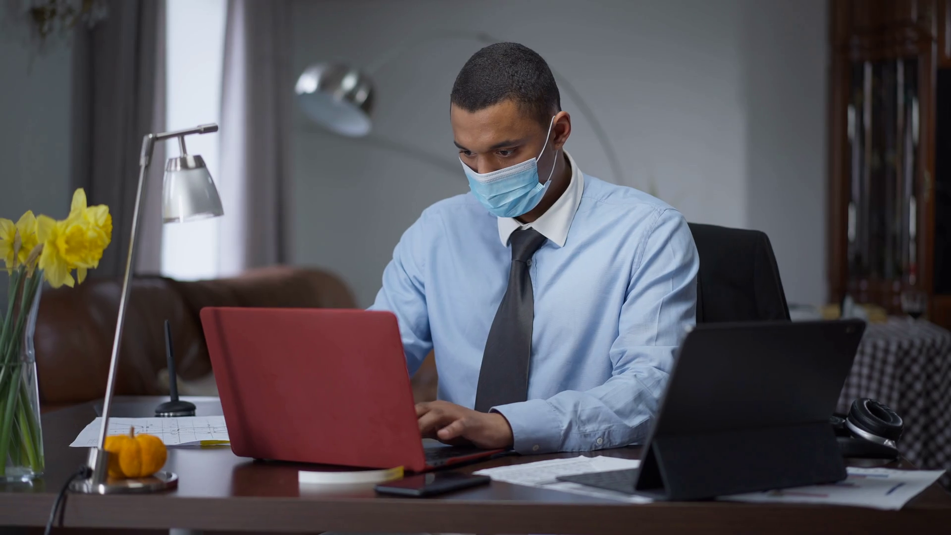 Portrait of overworking African American man in Covid face mask typing