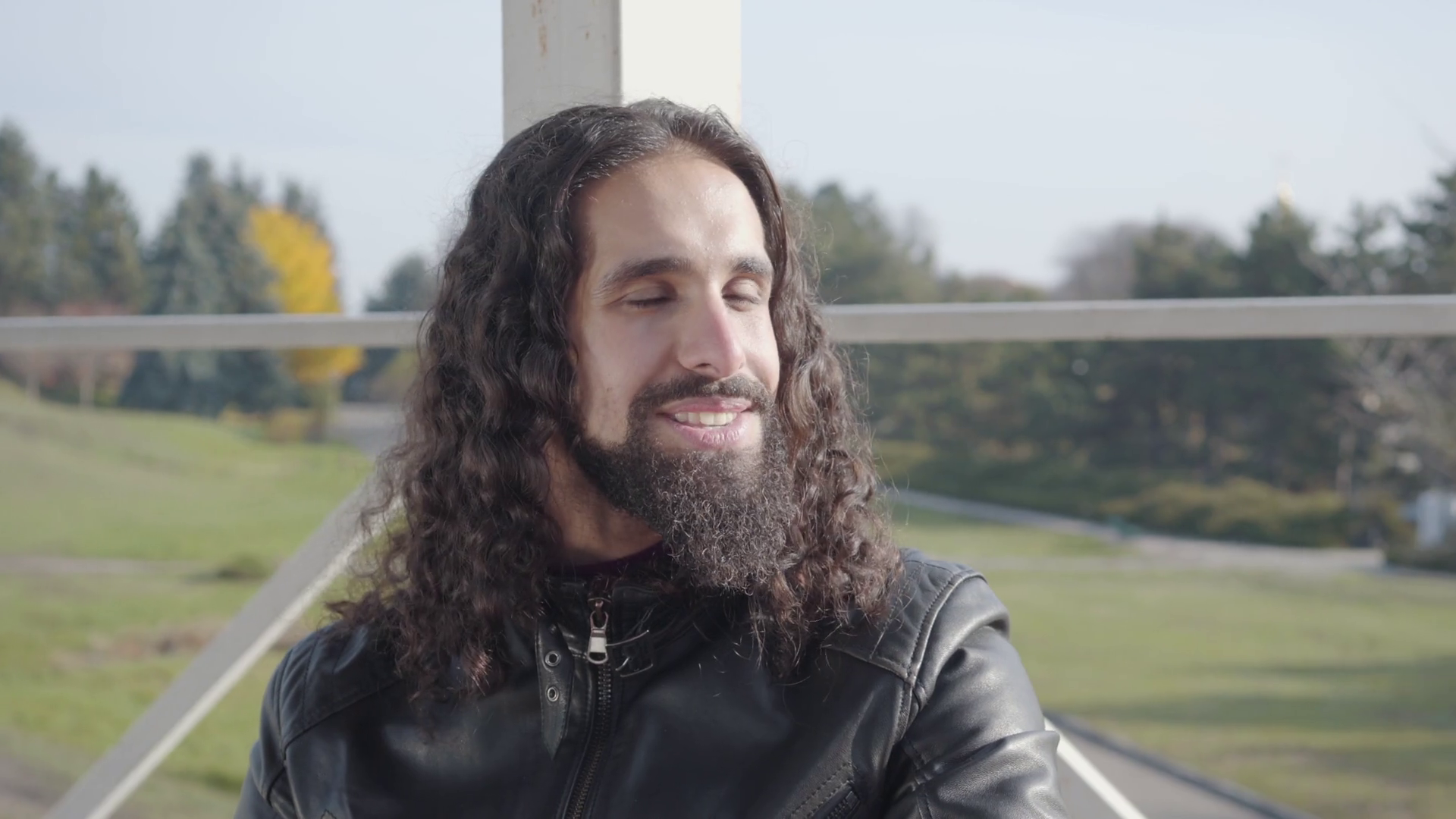 Portrait of positive hippie man with long curly hair and beard looking  away, talking and smiling. Close-up face of young Middle Eastern guy  resting in autumn park. Stock Video Footage 00:13 SBV-338160335 -