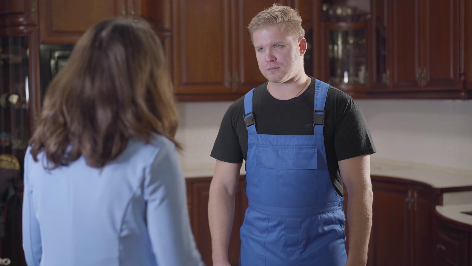 Portrait of annoyed Caucasian repairman in workrobe arguing with young brunette house owner. Professional man explaining woman her household problems