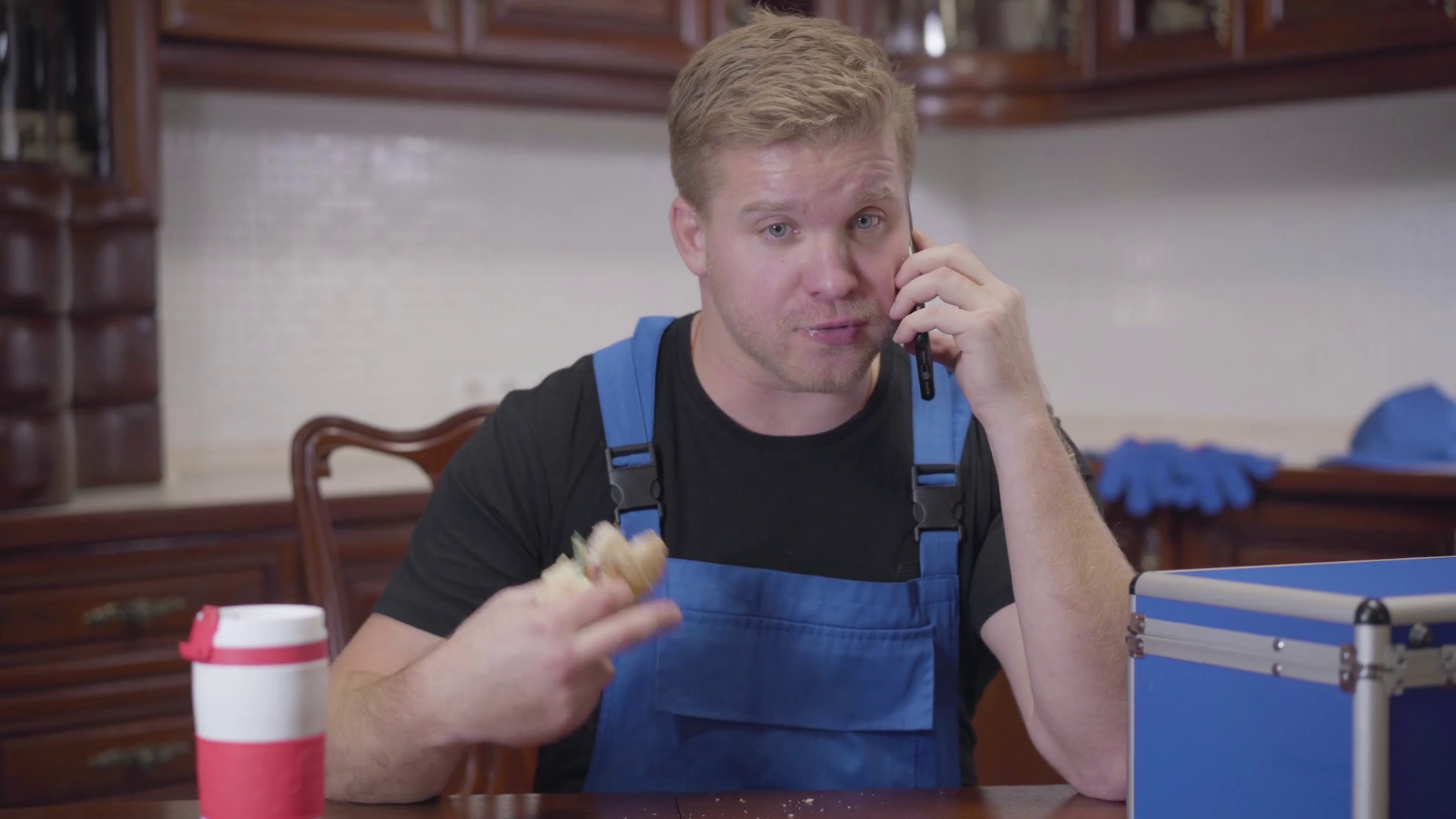 Portrait of young Caucasian plumber talking with customer on smartphone
