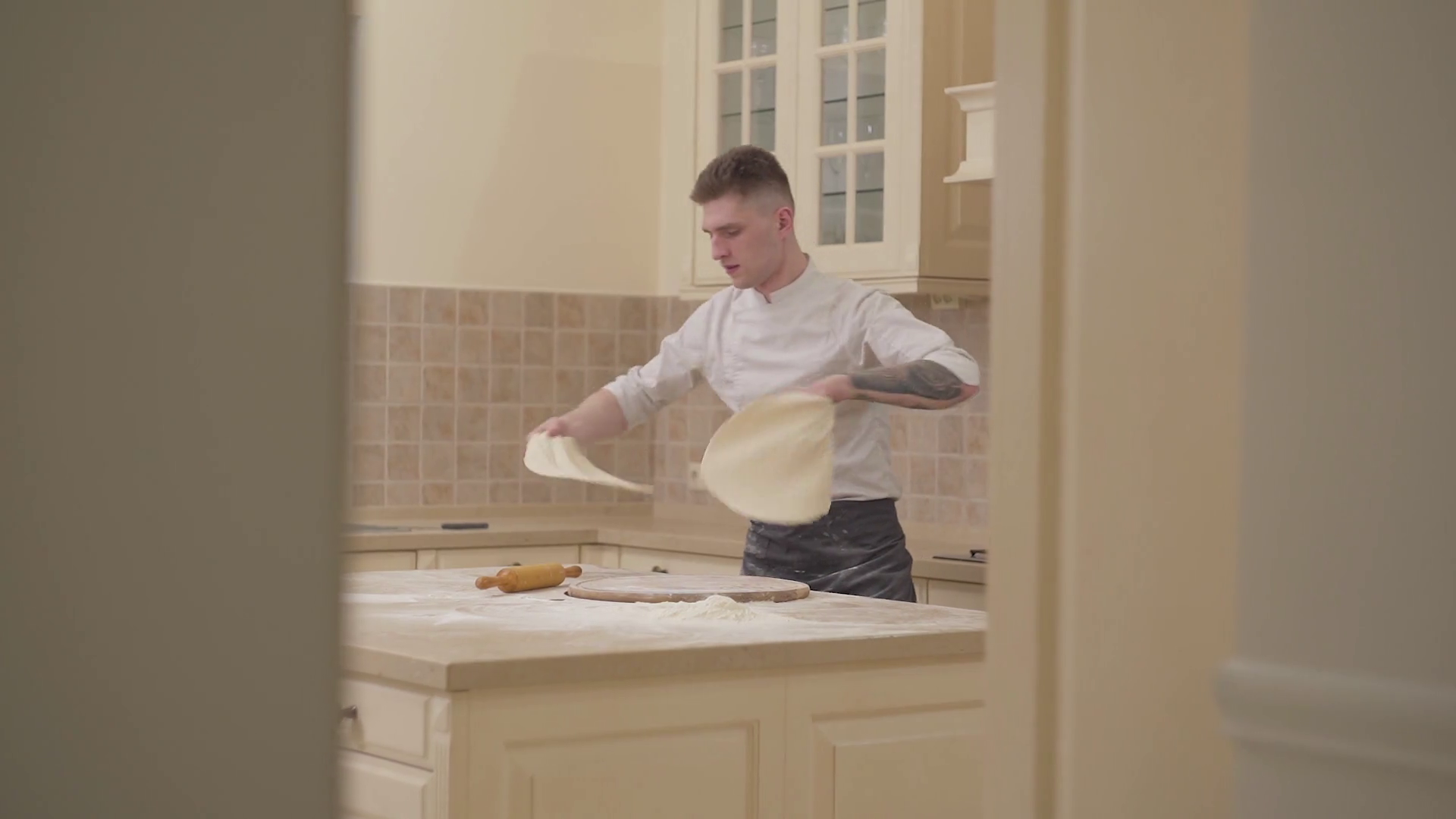 Slow motion of handsome young man spinning and tossing pizza dough up