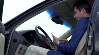 Successful businessman is having a business conversation in the car by phone