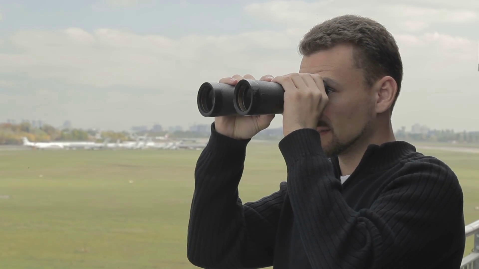 Young man with binoculars watches after planes in airport Stock Video