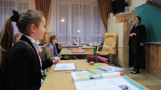 New York, USA - 13 July, 2018: Group of girls sitting at desks and throwing papers in classroom. Schoolchildren listening to teacher, smiling. Lesson. Indoors.