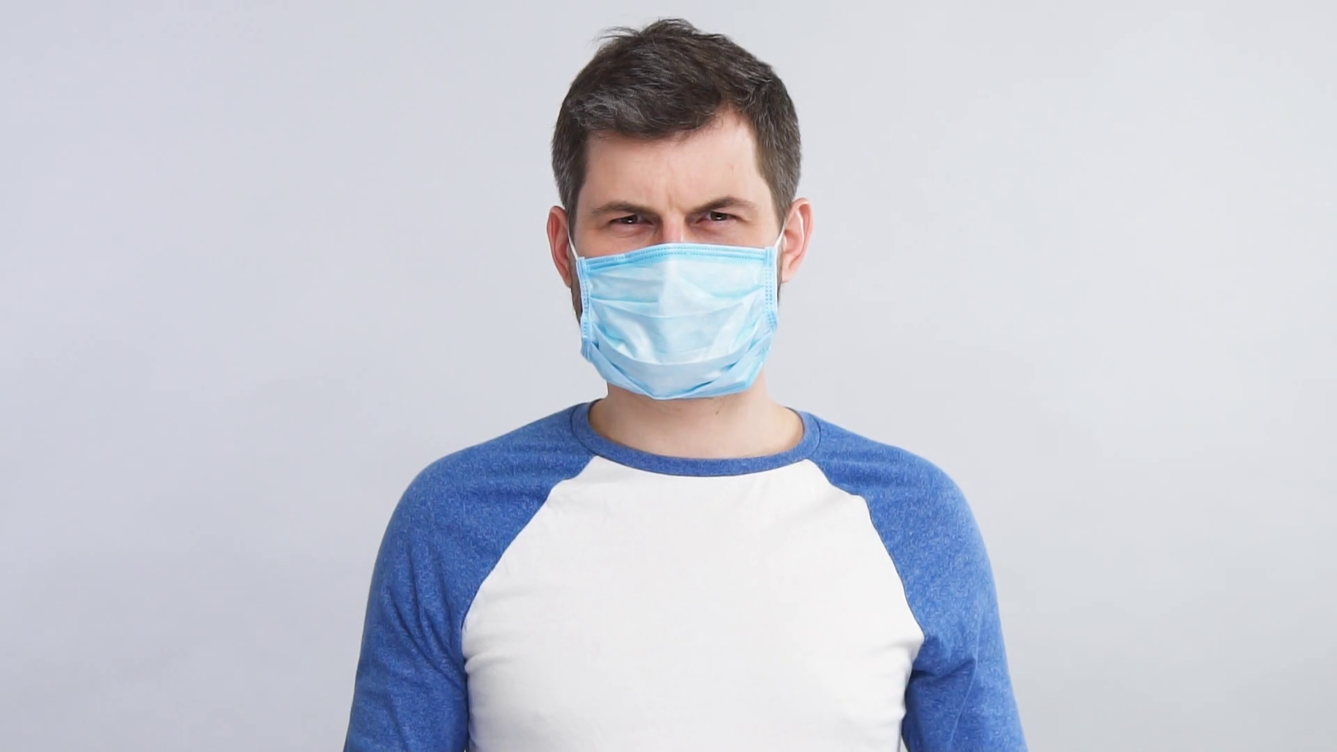 serious man in sterile mask distancing while coronavirus disease Stock