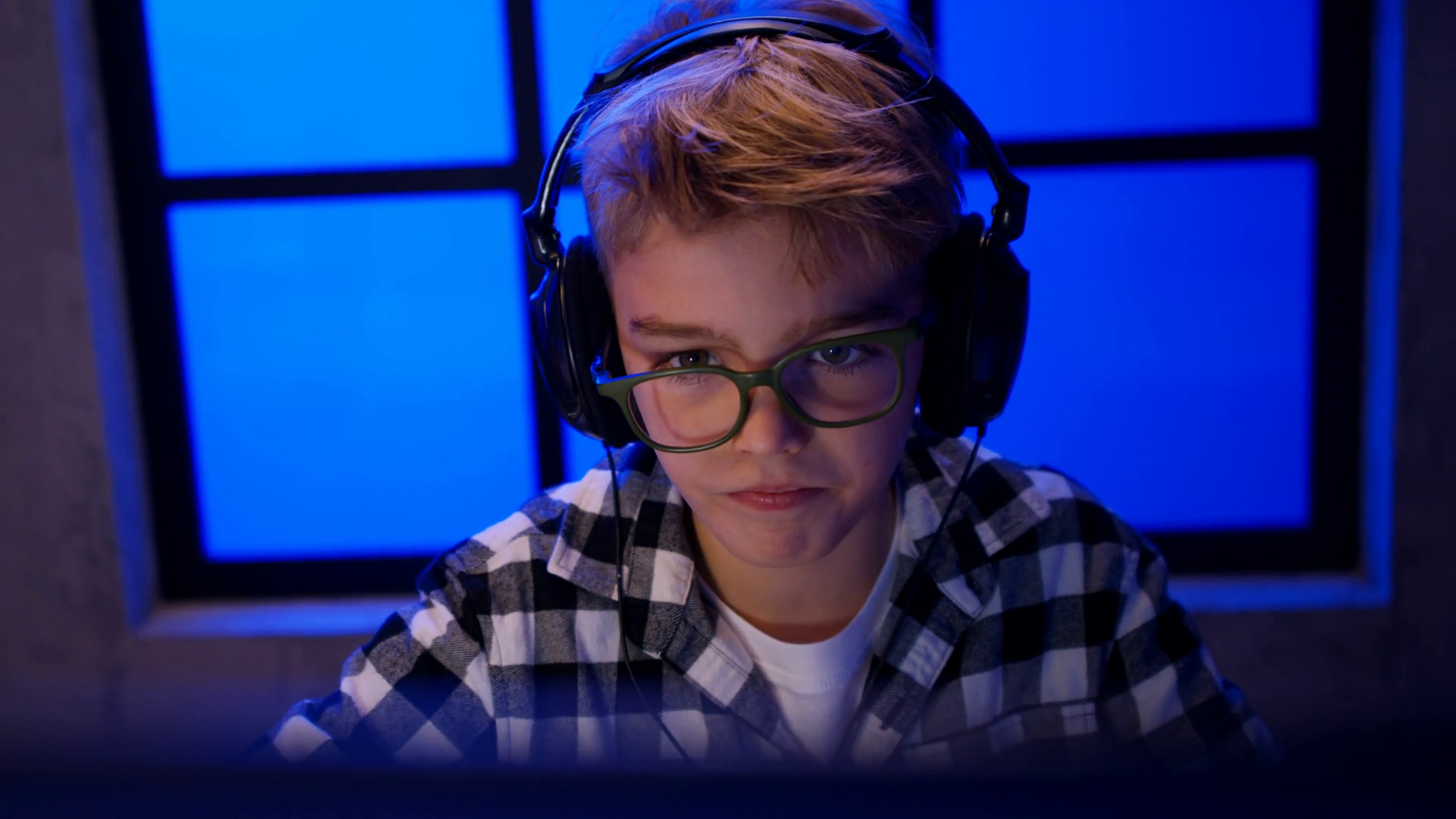 Young gamer boy with headphones playing computer video game. Stock