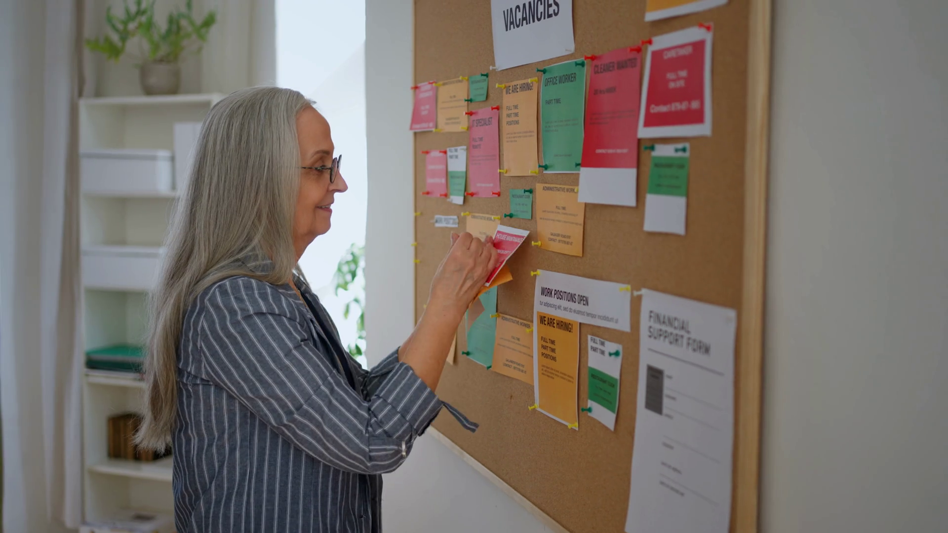 Job center employee pinning job vacancies on employment noticeboard ...