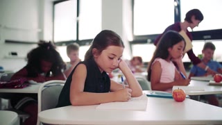 A focused student writing at her desk in class. Slow motion.