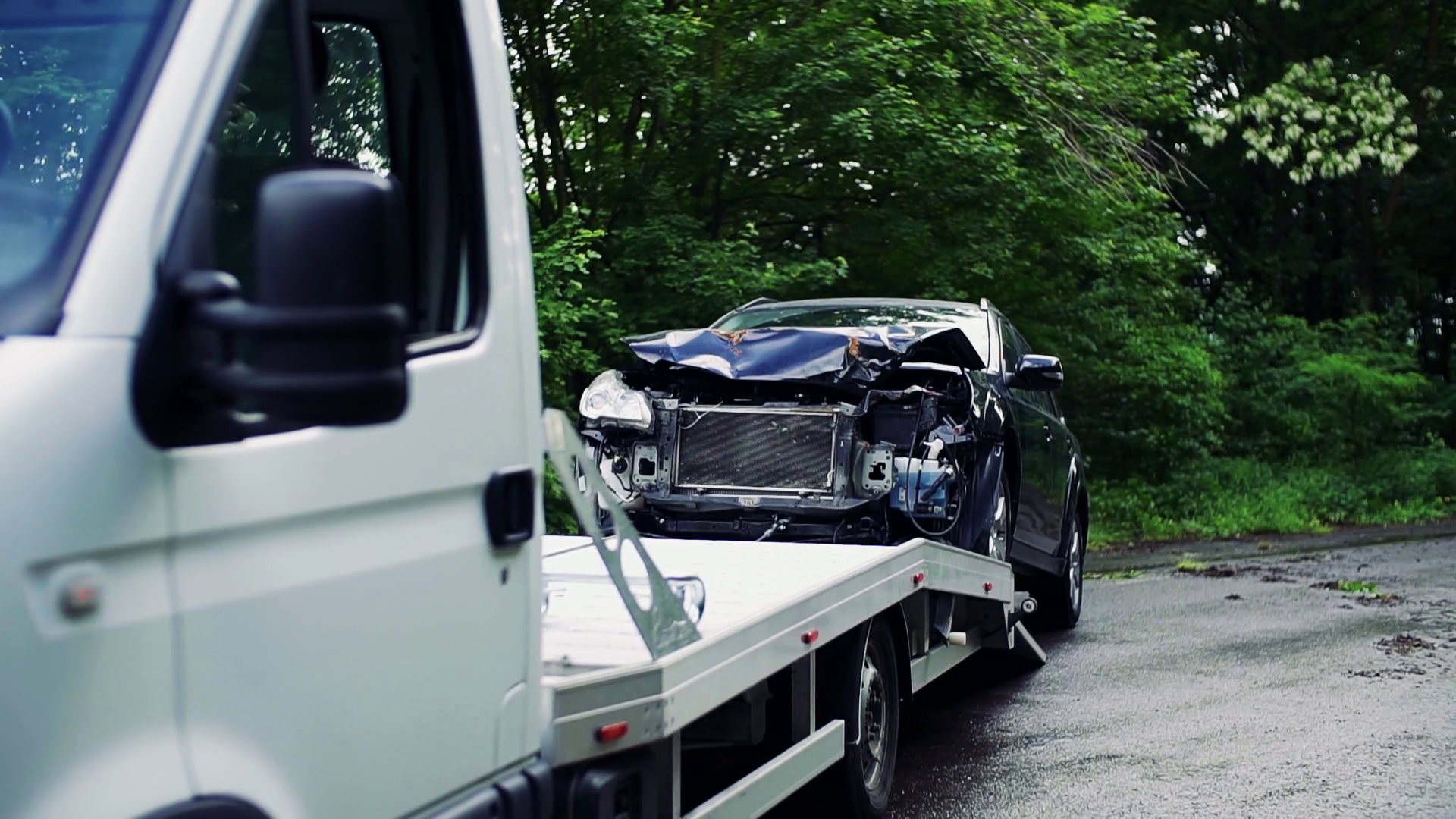 A crashed car being put on a tow truck after an accident