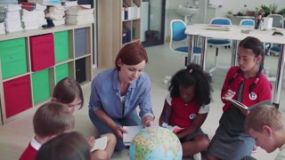 Young students learning geography in class with teacher. Slow motion.