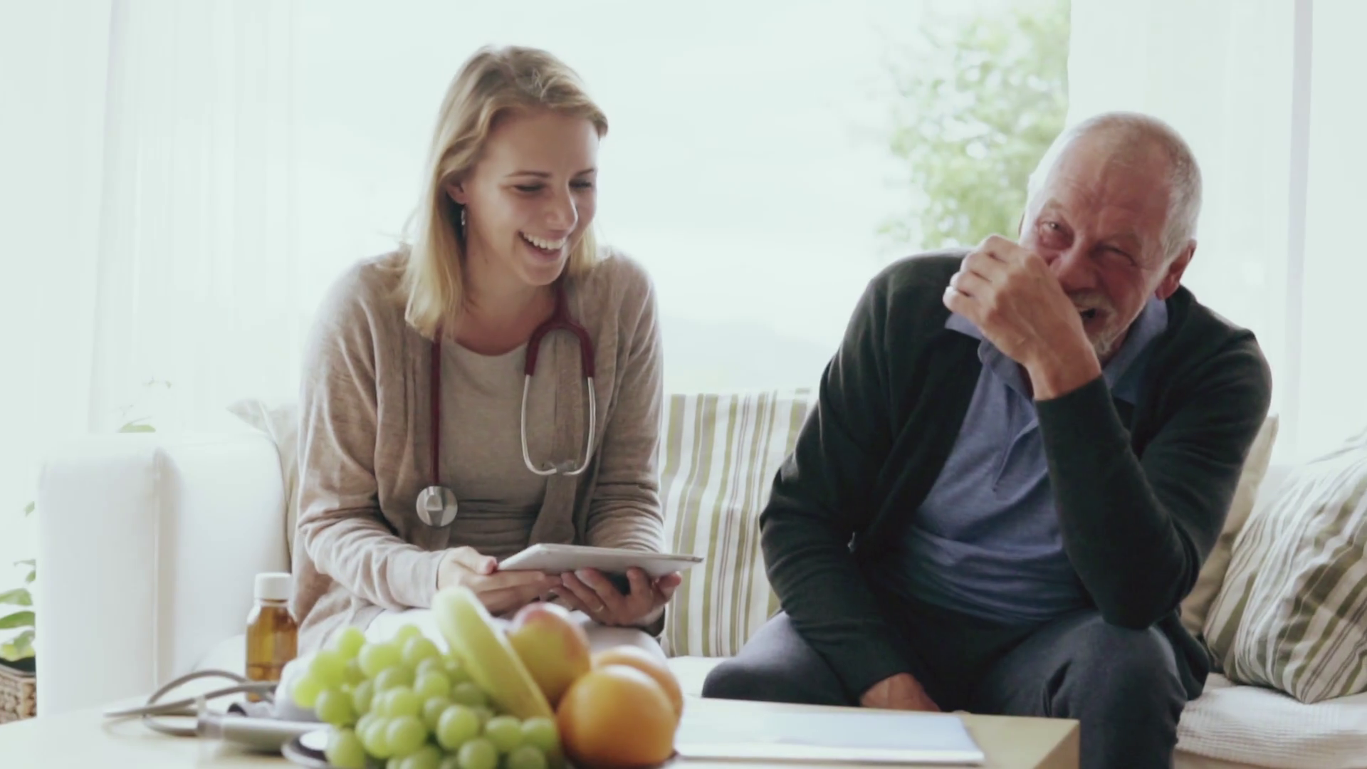Health visitor and a senior man with tablet during home ...