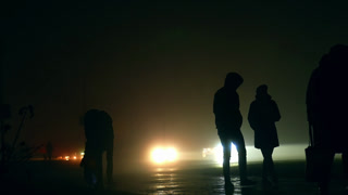 Wartime power blackouts in Ukraine. Dark silhouettes of people moving in the night time by the streets.