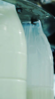 Milk is pouring into plastic bottles at a modern food factory. Footage of milk bottles at the production line in a milk company. Dairy production close-up. Vertical video