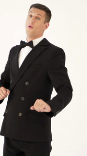 a showman in a stylish black suit with a bow tie is posing and walks out of sight on the white background. Vertical video