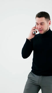 Young businessman talking on the phone. Handsome man in black sweater and grey trousers leading e-business through the cellphone. Man isolated on white. Vertical video