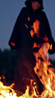 Witch conjure near bonfire. Close up of scary witch outdoors near bonfire. Vertical video