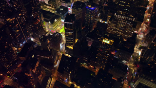 The dark tops of high buildings of New York at night. Drone flying over the lively metropolis with thousands of lights.