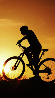 Healthy active lifestyle sports of fitness man exercising at sunset. Silhouette of an athlete cyclist man is drinking water after intensive cycling biking training. on the natural rural background. Vertical video