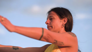 Young woman practicing serene yoga asana during golden hour, radiating wellness and inner peace against soft sunrise backdrop
