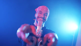Energetic african american man singing a song into a condenser microphone. The singer performs with passion in a music video production