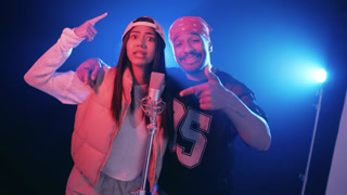 Dynamic singers performing a reggaeton track in a professional recording studio. Passionate male and female artists singing and dancing