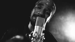 Black and white scene of a talented male rapper passionately singing into a vintage microphone. Smoky, dark background with spotlights