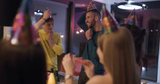 Friends Celebrate a Birthday Together, Wearing Party Hats and Blowing Party Horns While Having Fun at a Lively Party