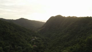 Aerial view of green valley with forest hills at sunset