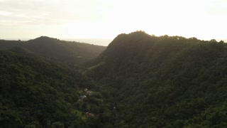 Aerial view of forest valley between green mountains at sunrise