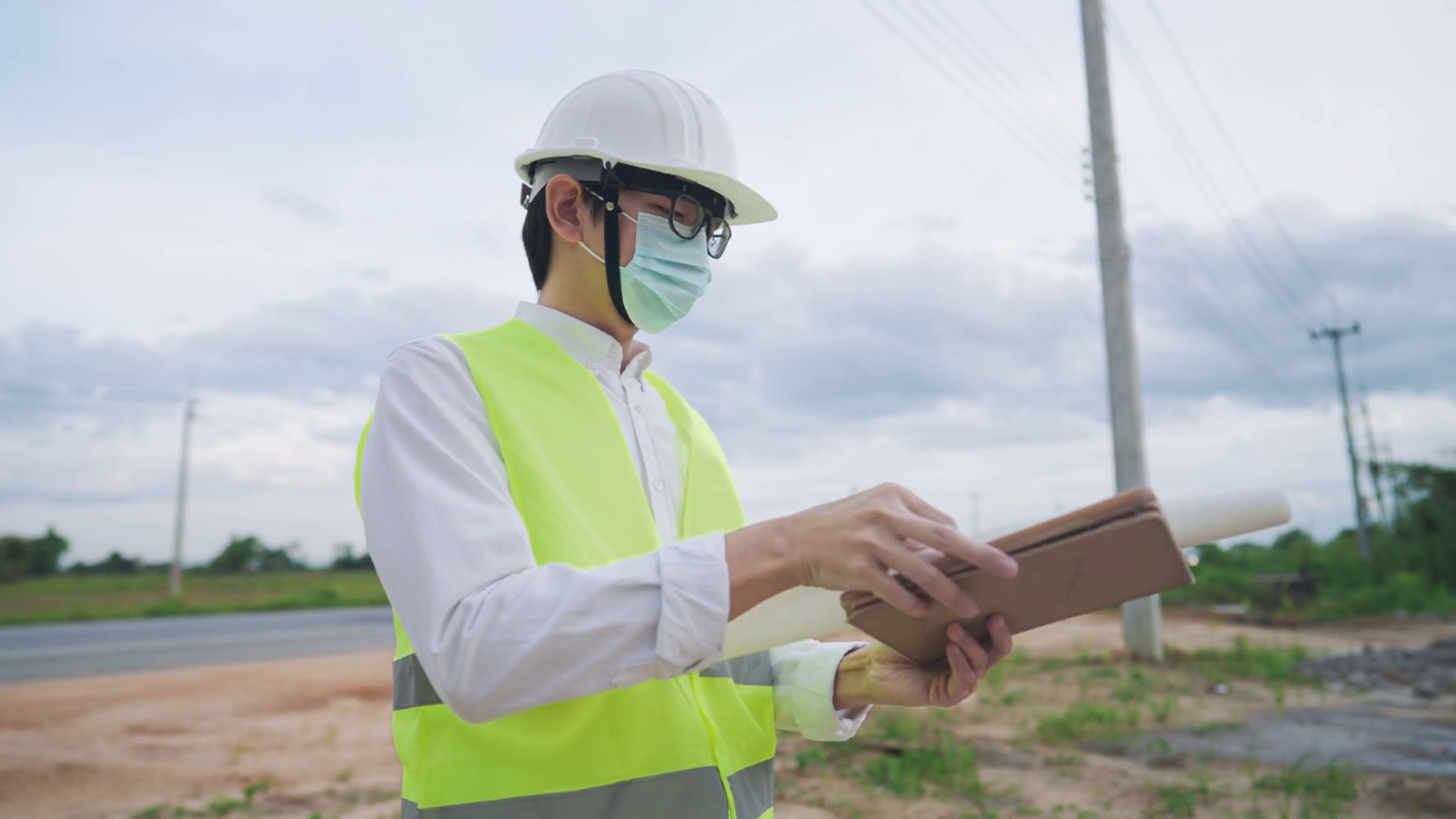 An electrical worker engineer working with digital tablet while standing on rural rough road