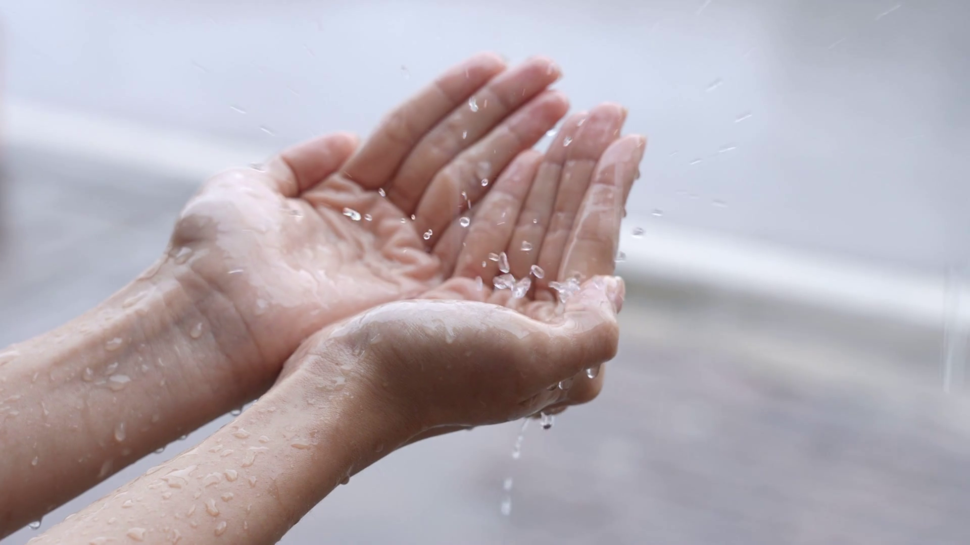 A female hands play catching rain drops on raining day caused by