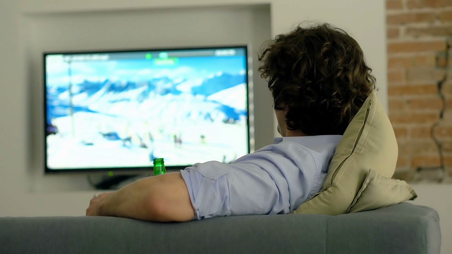 Man relaxing on the sofa at home and watching some tv programme Stock