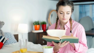 Relaxed person reading book and enjoying breakfast in bed, steadycam shot