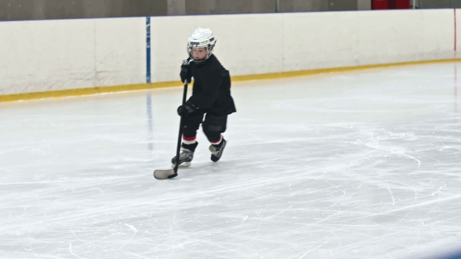Slow motion tracking shot of novice ice hockey player dribbling puck