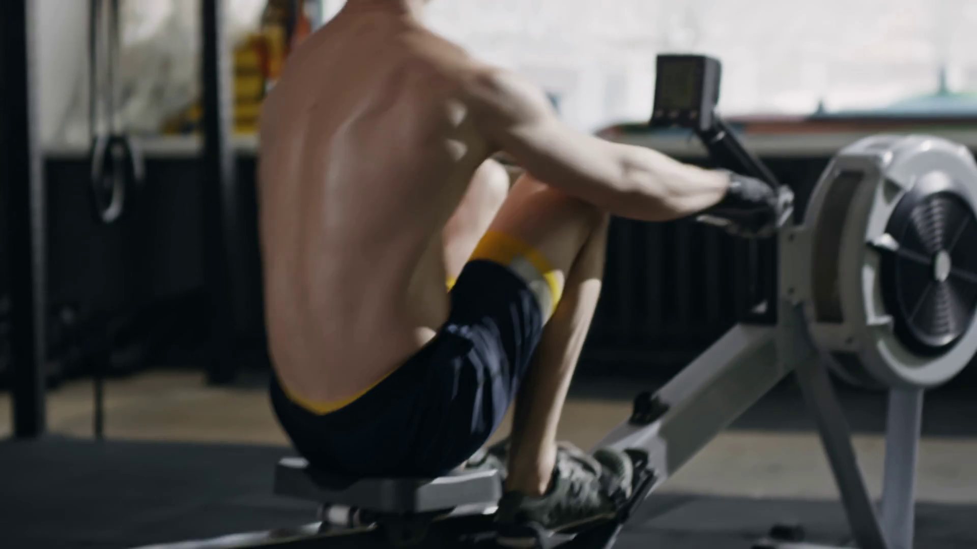 Tracking of sporty shirtless man working out on rowing machine and