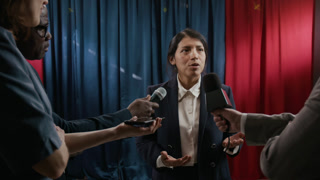 Hispanic young woman politician speaking to journalists holding microphones during press conference. Footage is suitable for political campaigns, news broadcasts, and election coverage