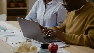 Close up shot of Black senior man using laptop and closing screen celebrating finishing tasks with young woman