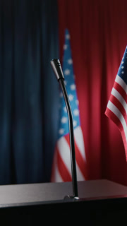 Microphone on empty podium with American flag in background, vertical. Clip is ideal for political news broadcasts, election campaigns, or government press releases, close up shot