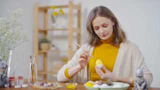 Young woman painting Easter egg and smiling