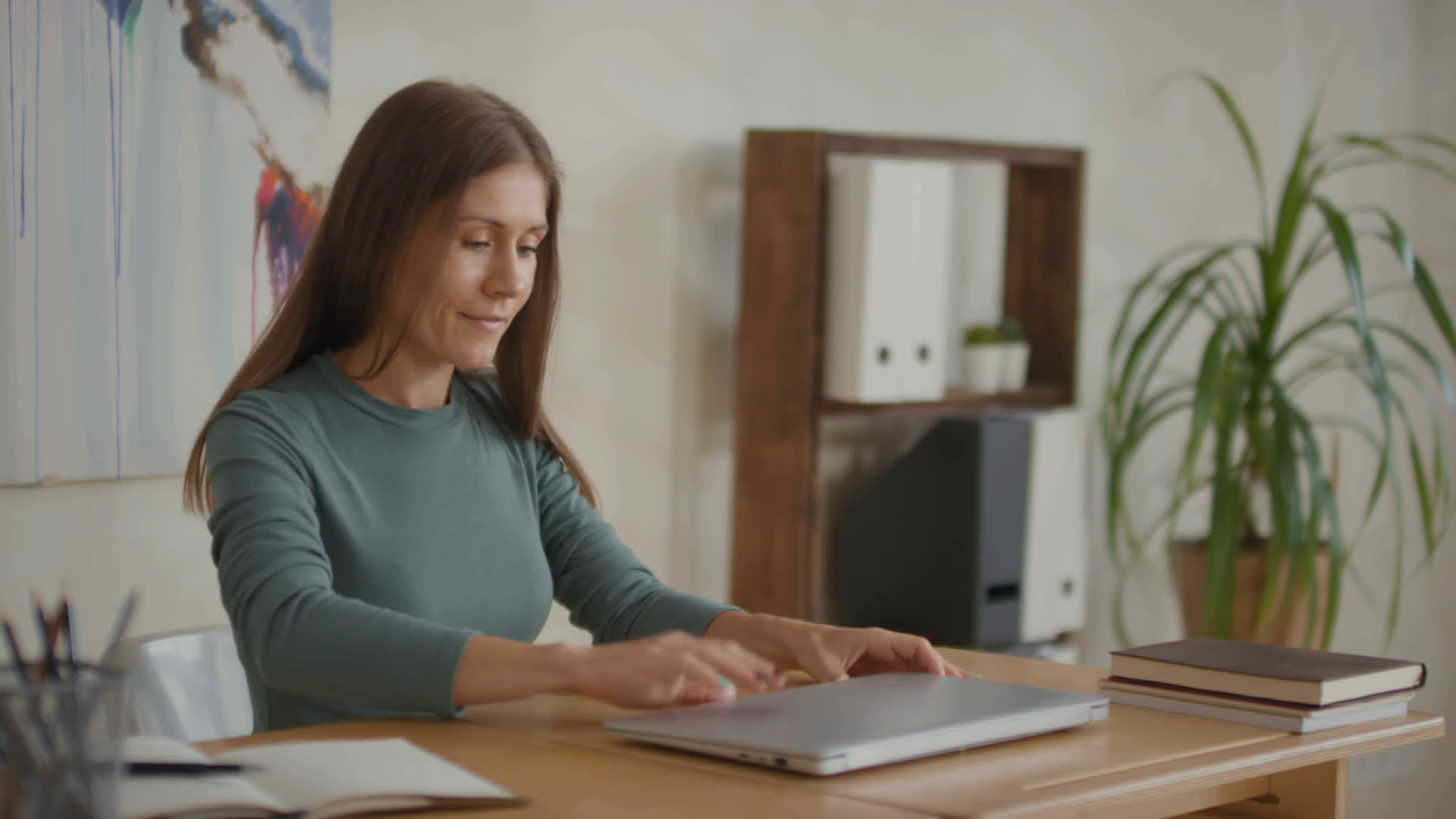 Medium shot of caucasian woman sitting at desk, opening laptop and