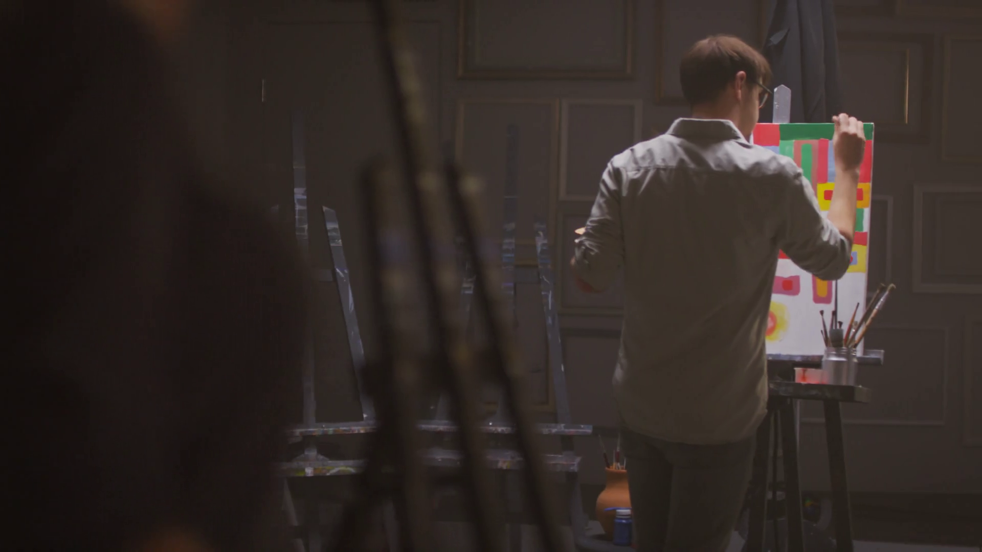 Medium shot of elegant female artist entering dark art studio where man