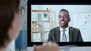 Rack focused shot of african american businessman discussing project with female colleague via video call on computer