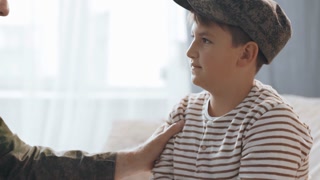 Slowmo close up of happy bearded army soldier in military uniform smiling and saying goodbye to his son before leaving for deployment