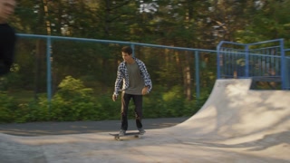 Slow-motion tracking shot of individuals skateboarding on ramp in skatepark