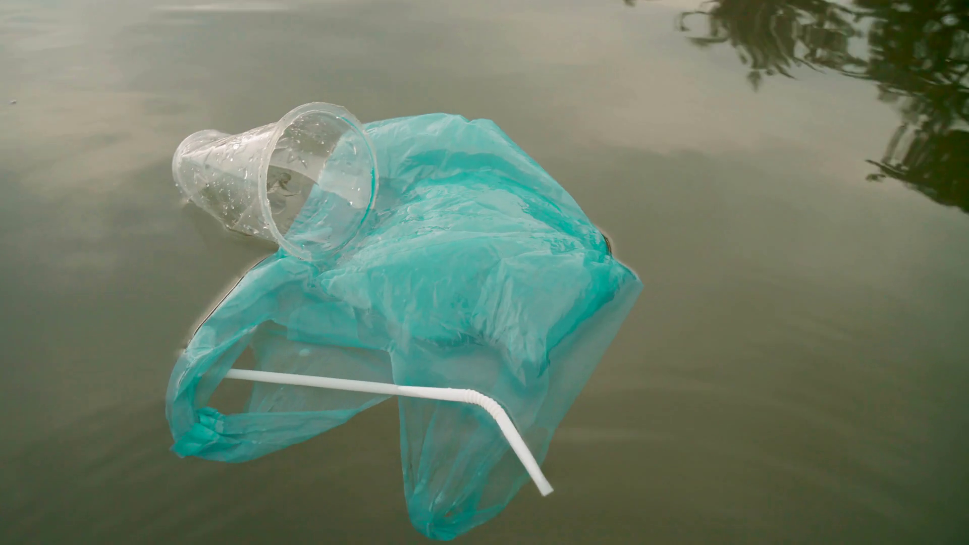 Topview shot of such trash as plastic bags, straws and cups floating