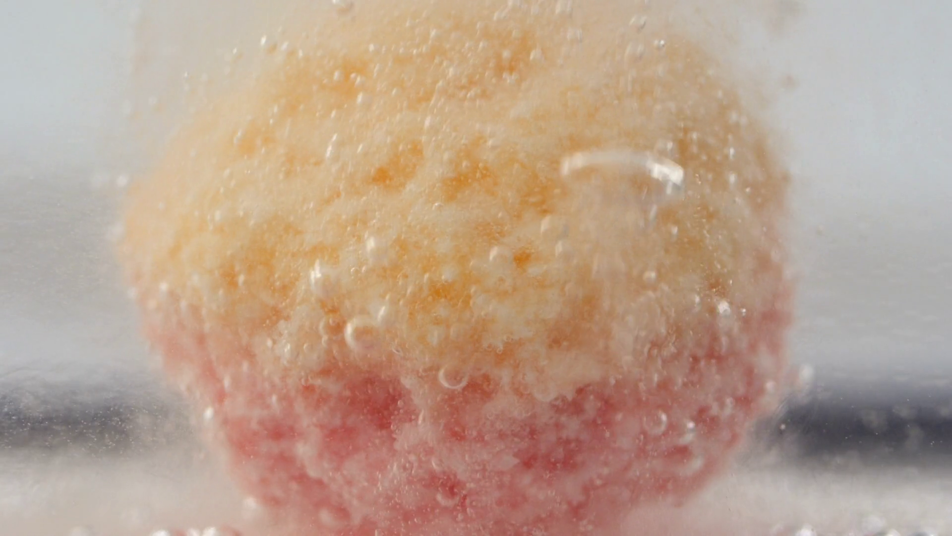 Underwater close up view of colorful bath bomb exploding and forming small bubbles in clean
