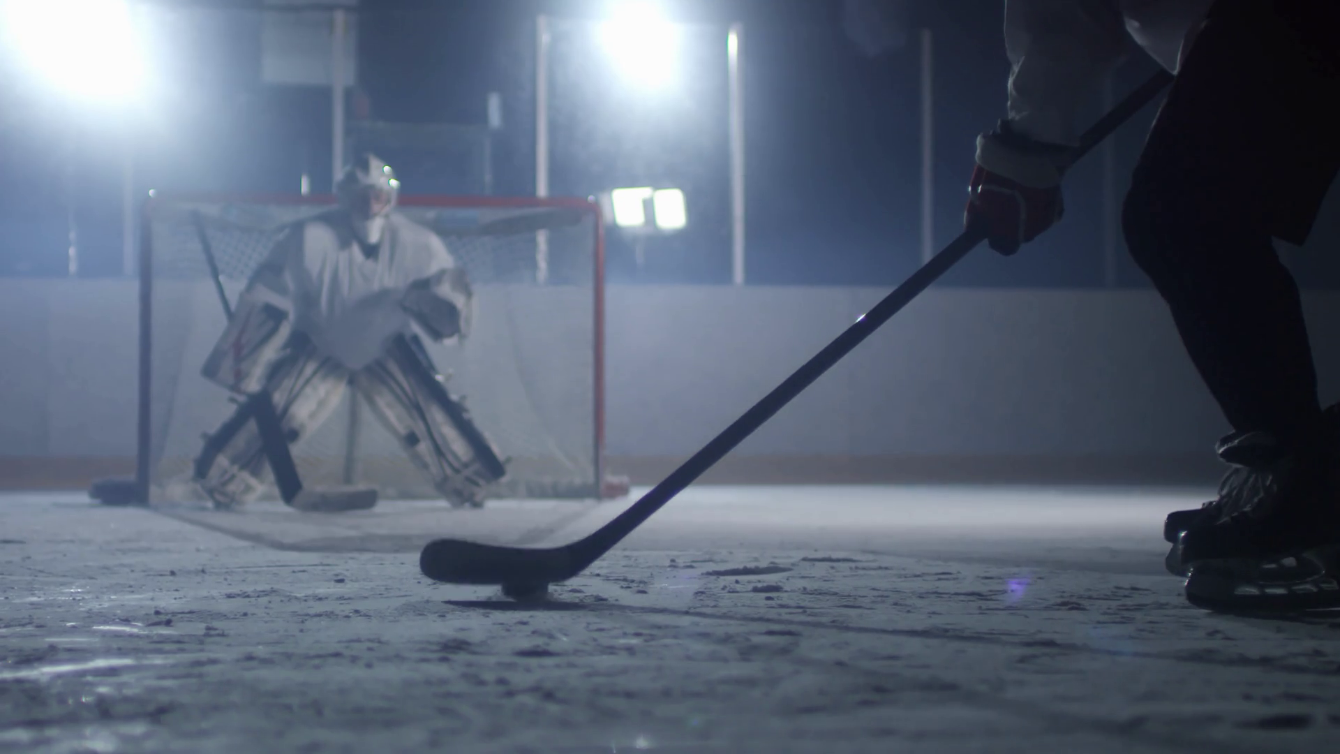 Unrecognizable hockey player preparing to shoot puck, goaltender