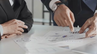 Close up midsection slowmo shot of unrecognizable businessman standing and explaining project efficiency to business associate using charts in documents during office meeting