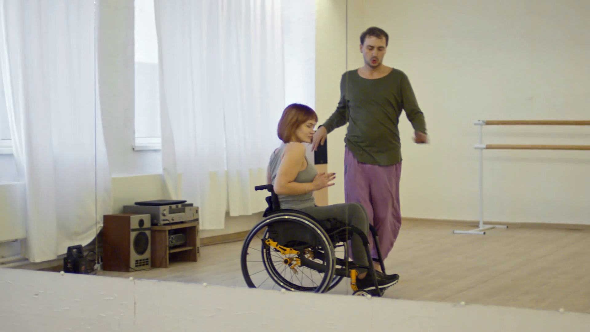 Young woman with paralyzed legs dancing in wheelchair with male