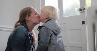 Mother and child kissing goodbye at home